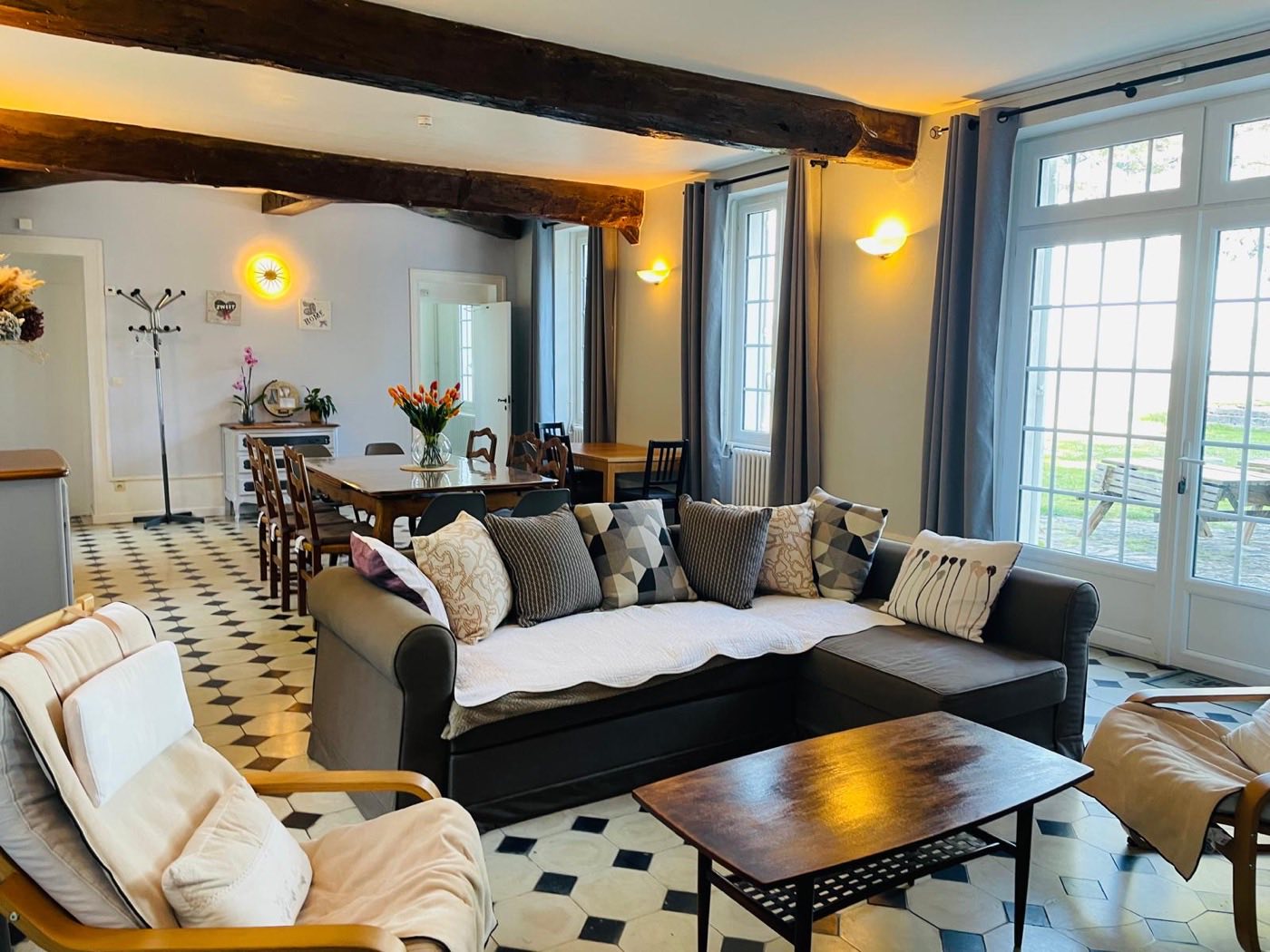 Grand salon du gîte du Manoir de la Houlette — canapés, poutres apparentes et carrelage damier, Normandie