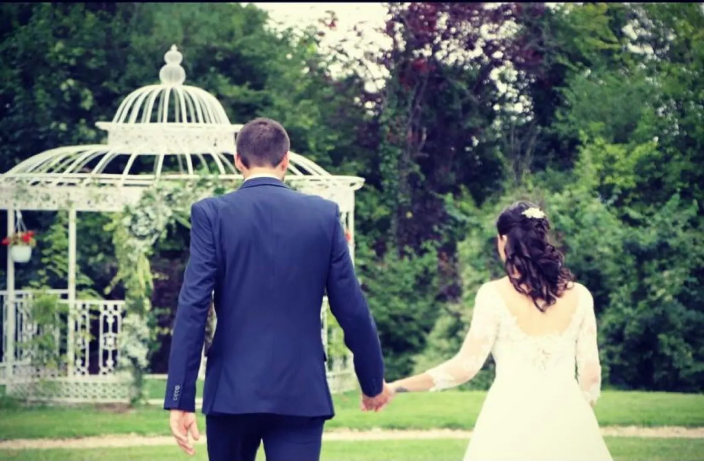 Les mariés main dans la main vers le gazebo du parc du Manoir de la Houlette — mariage en Normandie, Eure